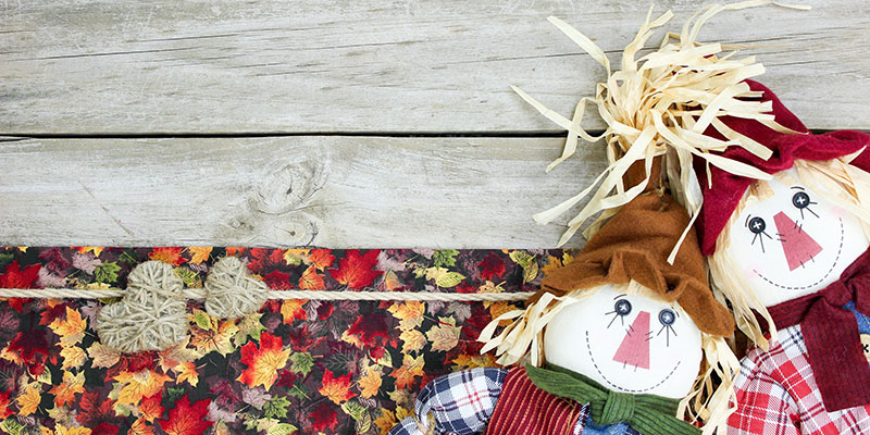 Two scarecrow dolls on fall background.
