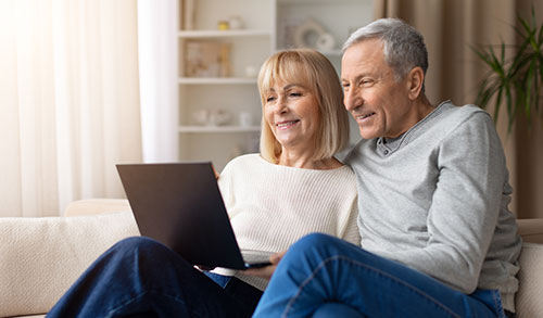 Senior couple sitting and looking at laptop
