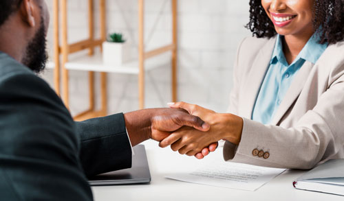 African American man and women shaking hands over desk.
