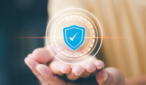 Two hands holding a glowing tranlucent circle with a blue shield containing a checkmark.