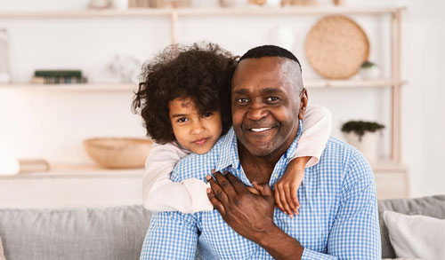 Older man with child hanging over his shoulder.