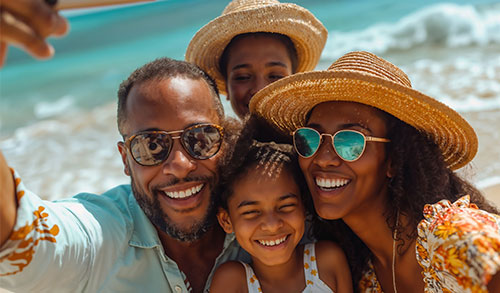 Family of four on vacation at beach taking a selfie.
