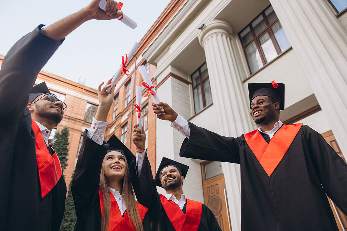 Multi-ethnic group of graduates smiling in their caps and gowns.